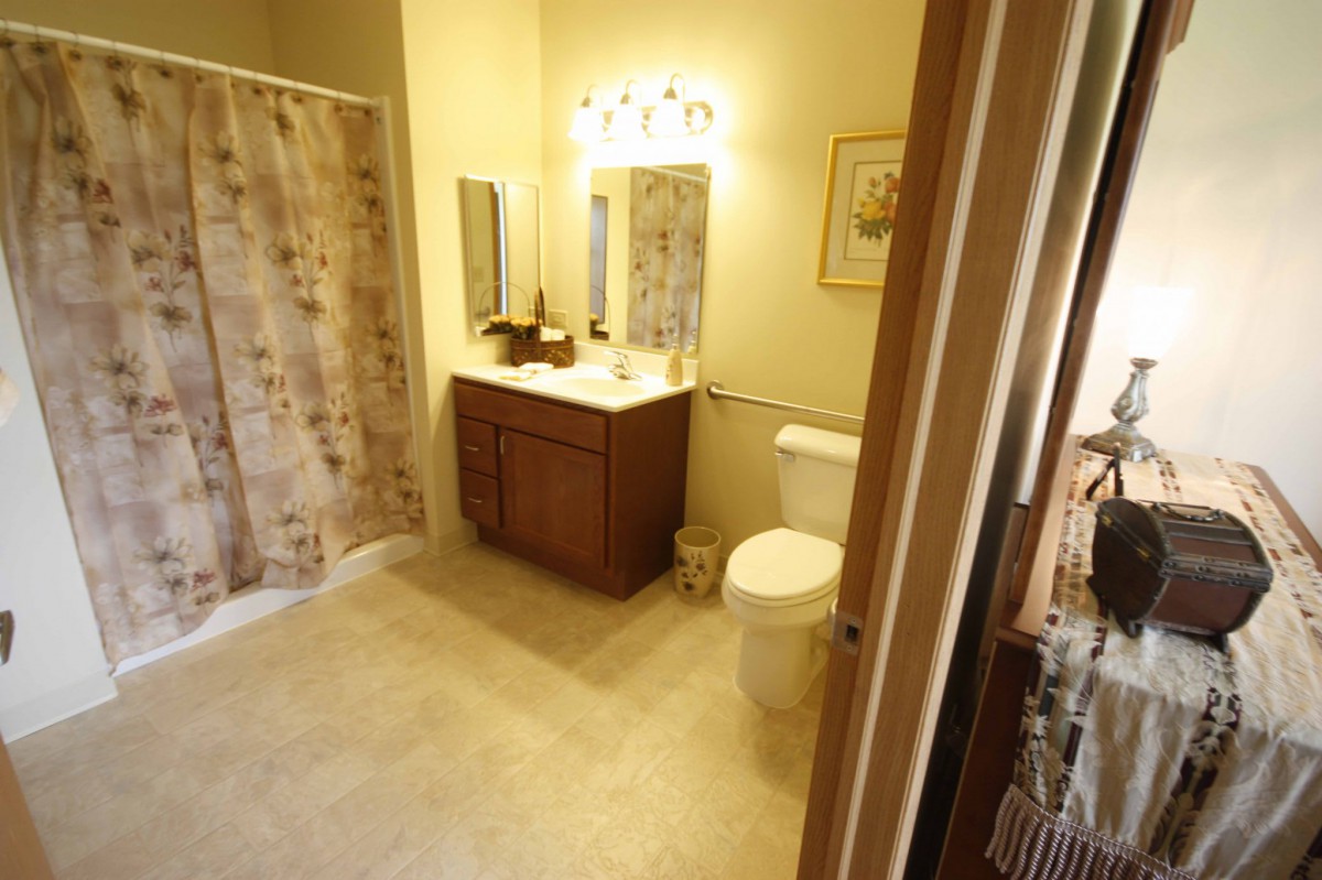 A clean and well-lit bathroom featuring a vanity with a sink, a toilet, and a shower area.