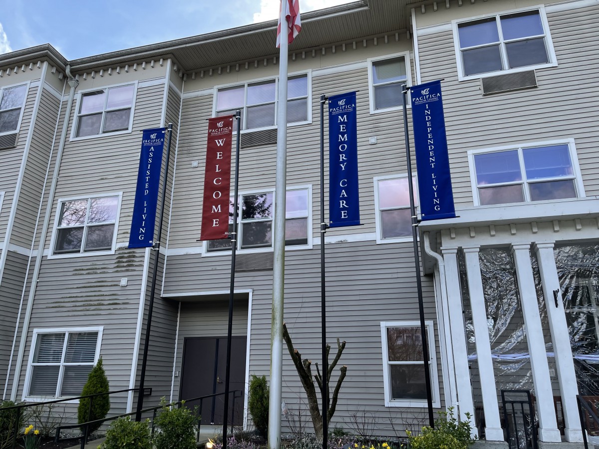 An apartment building with welcome signage and multiple flags displayed outdoors.