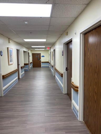 A corridor in a hospital with wooden doors and artwork on the walls.
