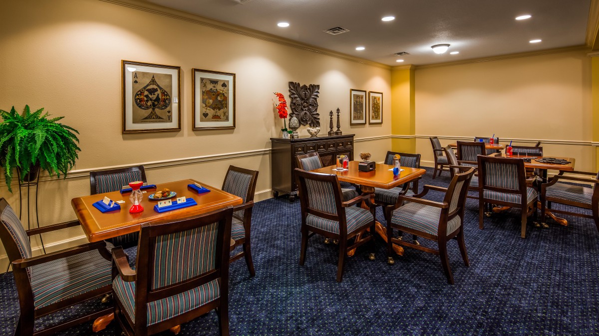 A cozy dining area with neatly arranged tables and chairs, decorated with wall art and ambient lighting.