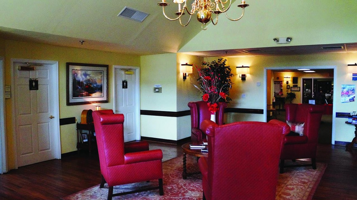 A cozy lobby area featuring red chairs, a chandelier, and decorative elements.