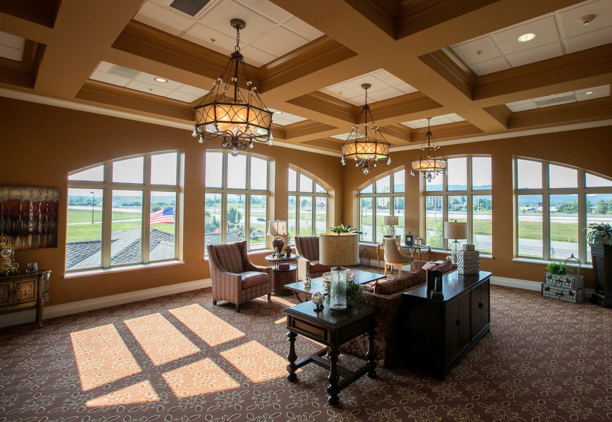 A spacious lounge with large windows, comfortable seating, and elegant chandeliers.