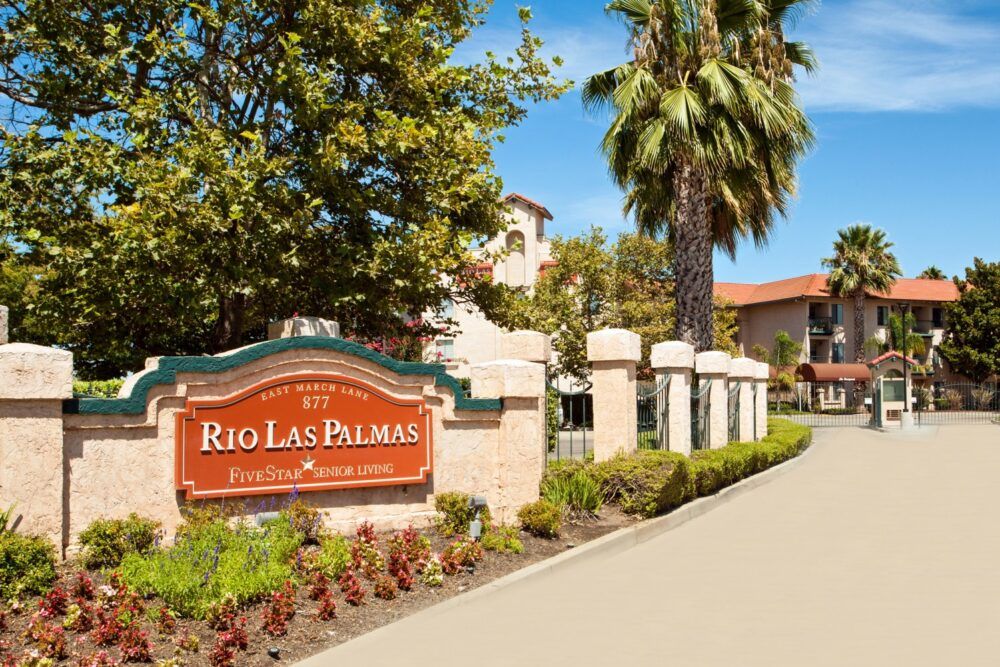 Entrance to the Rio Las Palmas apartment complex with well-maintained landscaping and palm trees.