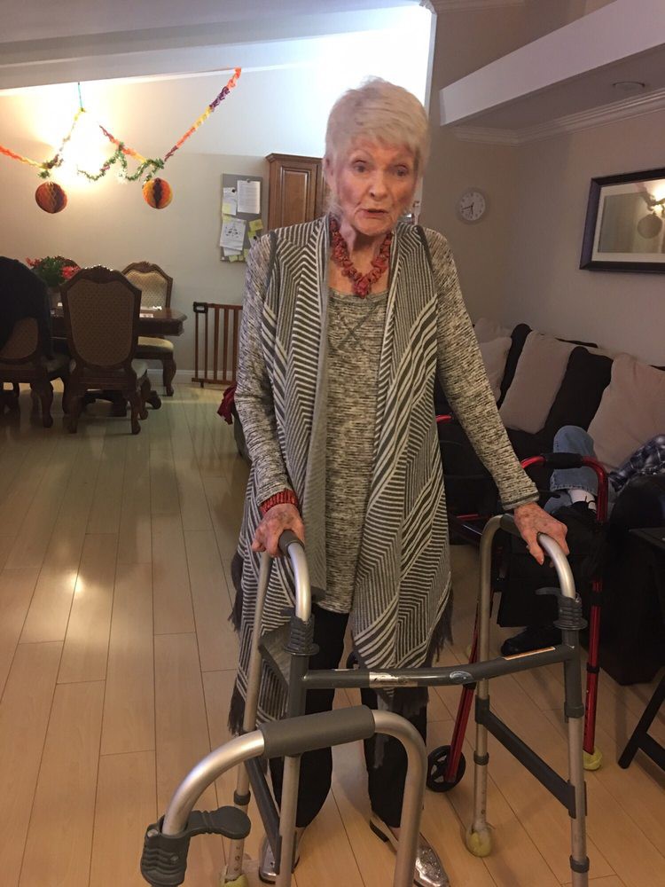 An elderly woman using a walker in a living room setting.