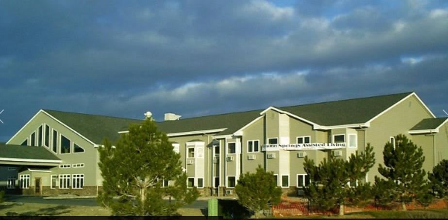 A large building with a cloudy sky and trees in the foreground.