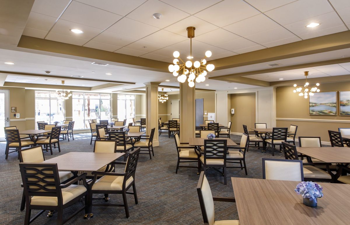 A modern and spacious dining room with elegant chandeliers and neatly arranged tables and chairs.