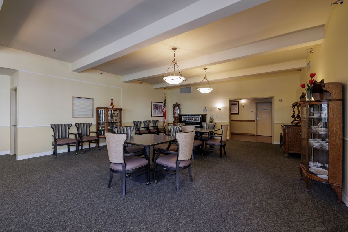 A spacious dining area with neatly arranged tables and chairs, adorned with elegant lighting.