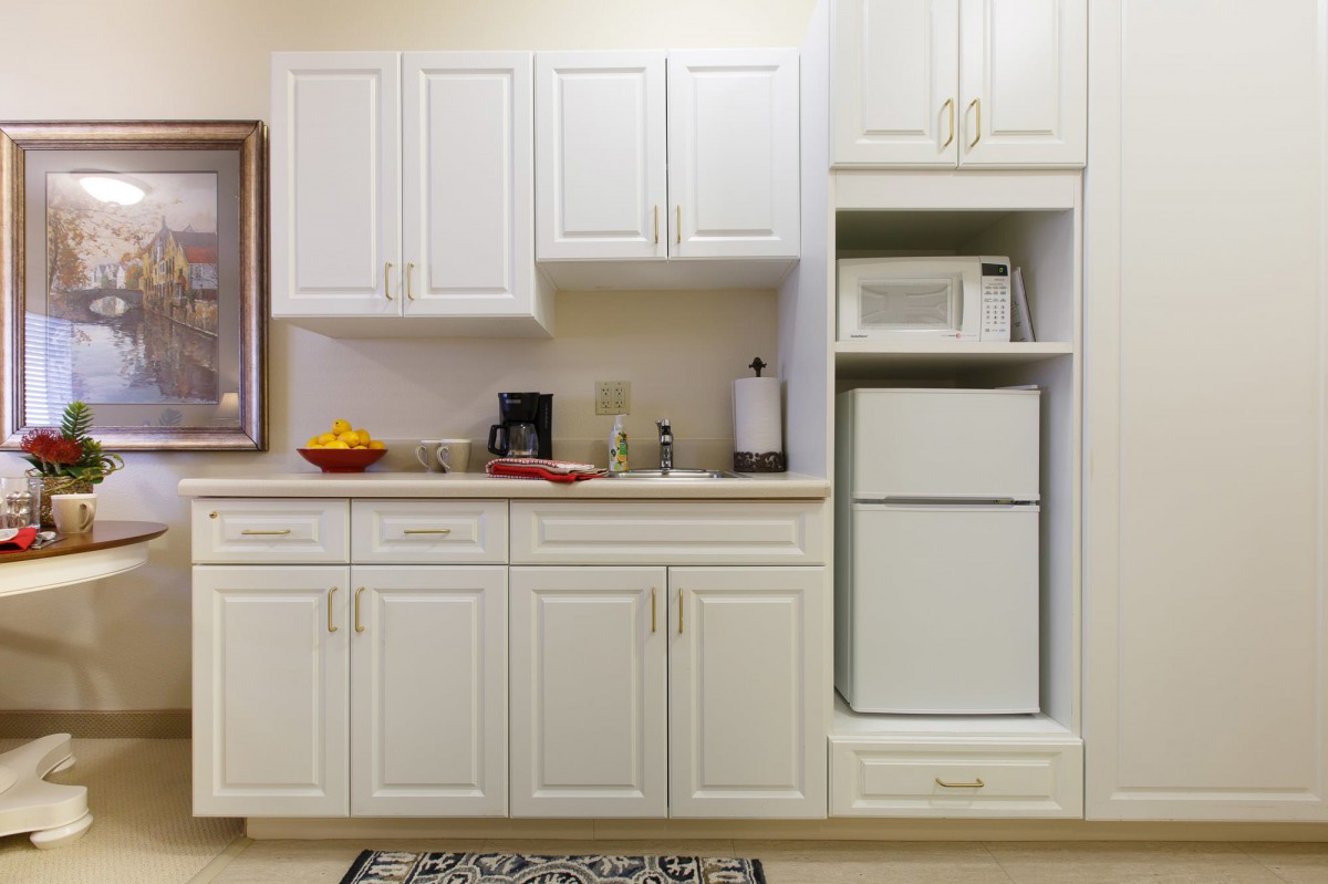 A compact kitchen setup featuring white cabinets, a microwave, and a refrigerator.