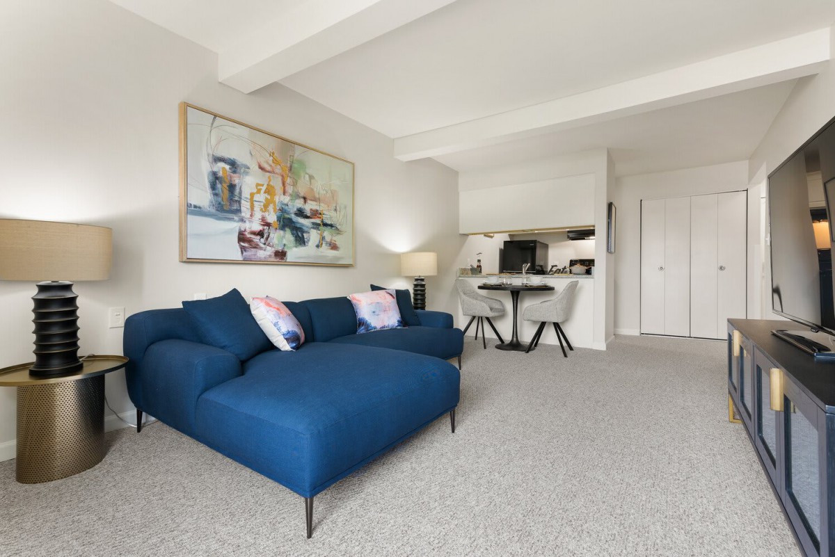 A modern, minimalist living room with a blue sofa and contemporary artwork on the wall.