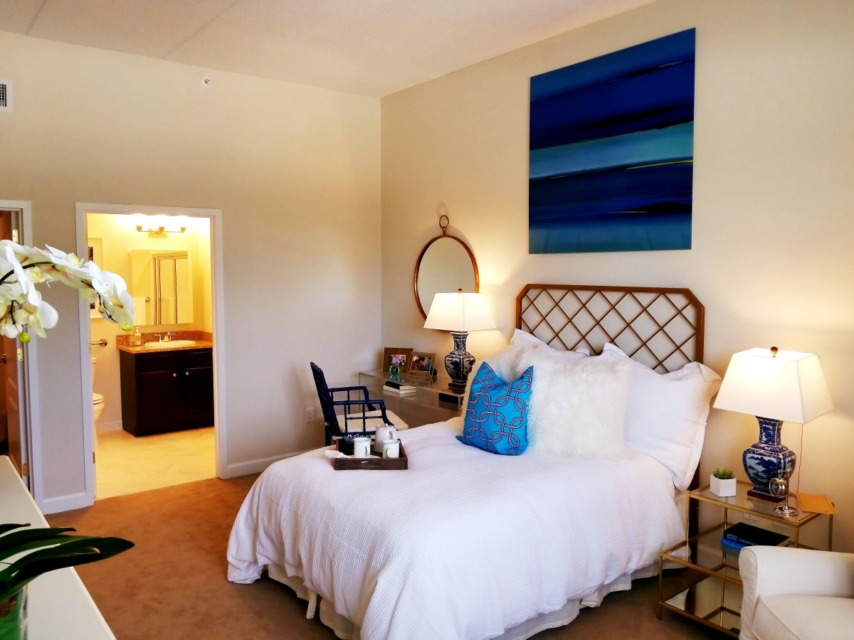 A cozy bedroom featuring a stylish bed, decorative pillows, and a modern painting on the wall.