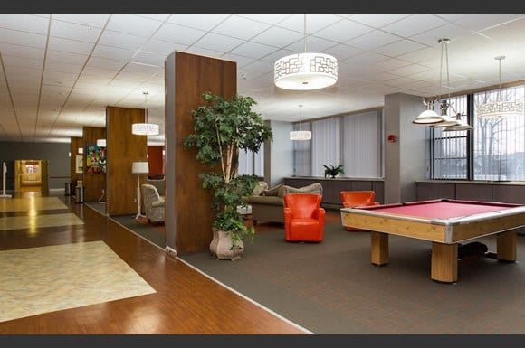 A modern lounge area featuring a pool table, comfortable seating, and stylish lighting.