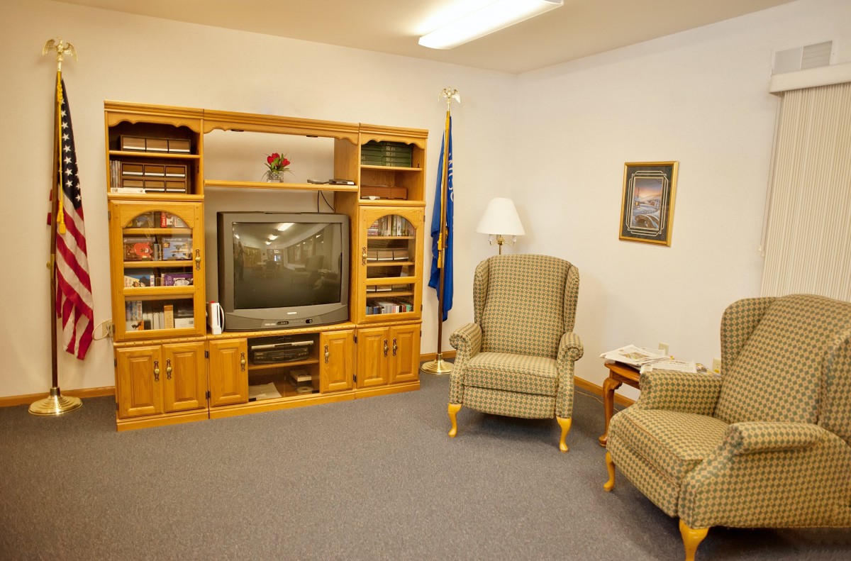 A cozy living room with an entertainment center and armchairs.