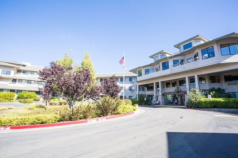 A large residential building with a landscaped entrance and an American flag.