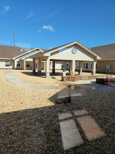 A view of a modern residential building with an open courtyard, surrounded by gravel and a clear blue sky.