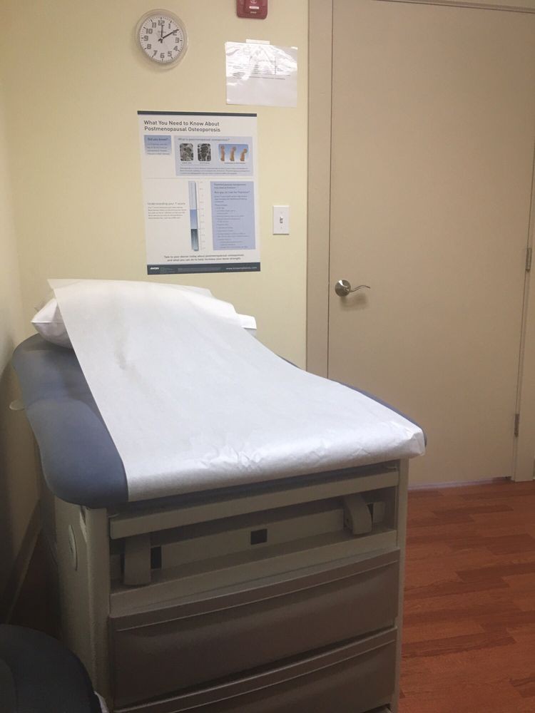 A medical exam room featuring an examination table with disposable paper covering.