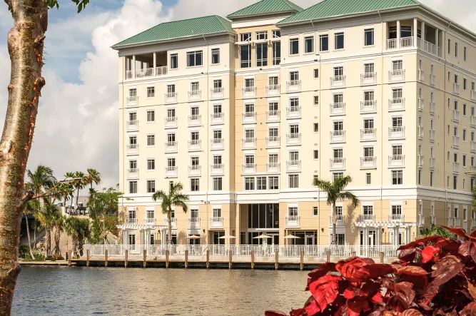 A waterfront hotel with palm trees and a serene atmosphere.