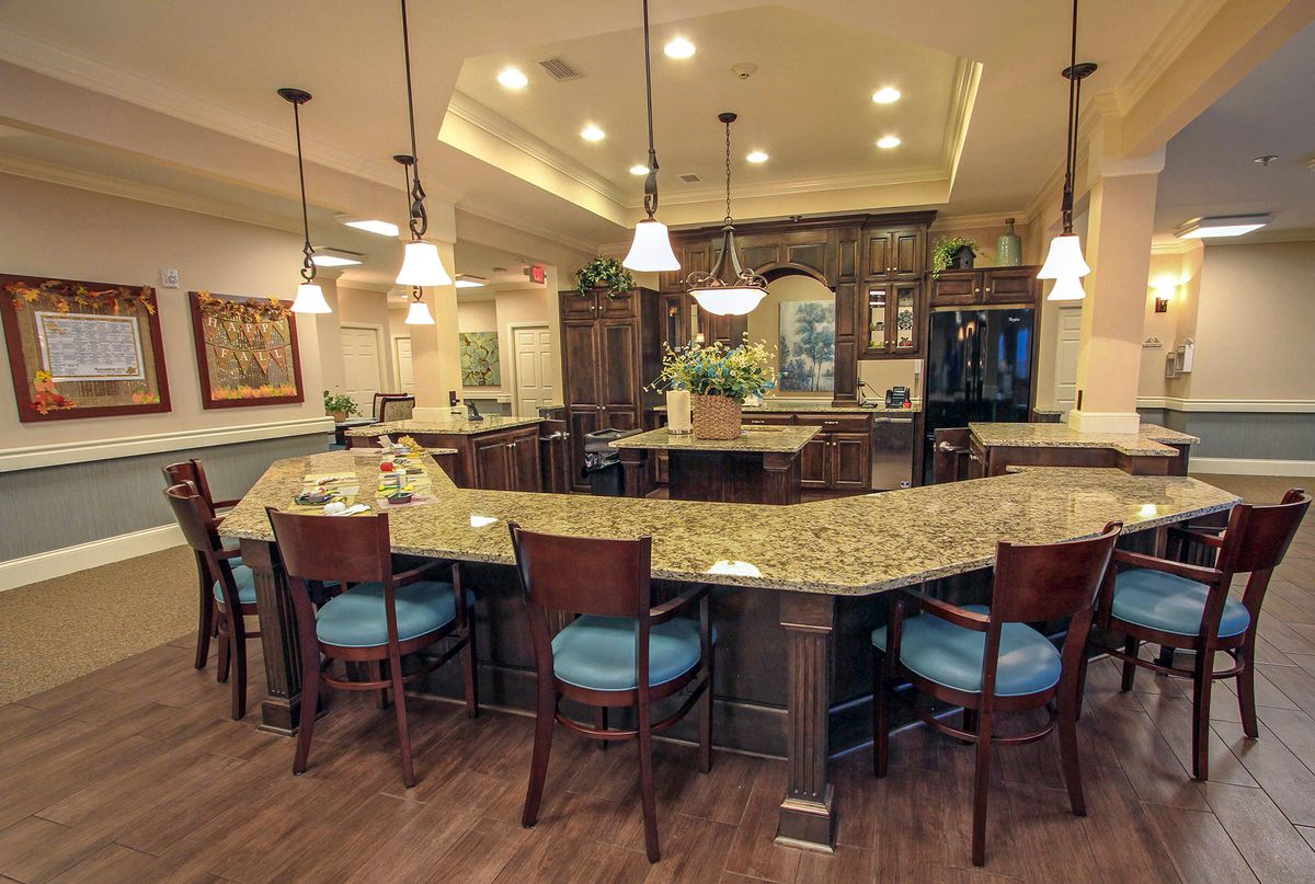 A modern kitchen with a large countertop and bar seating, illuminated by pendant lights.