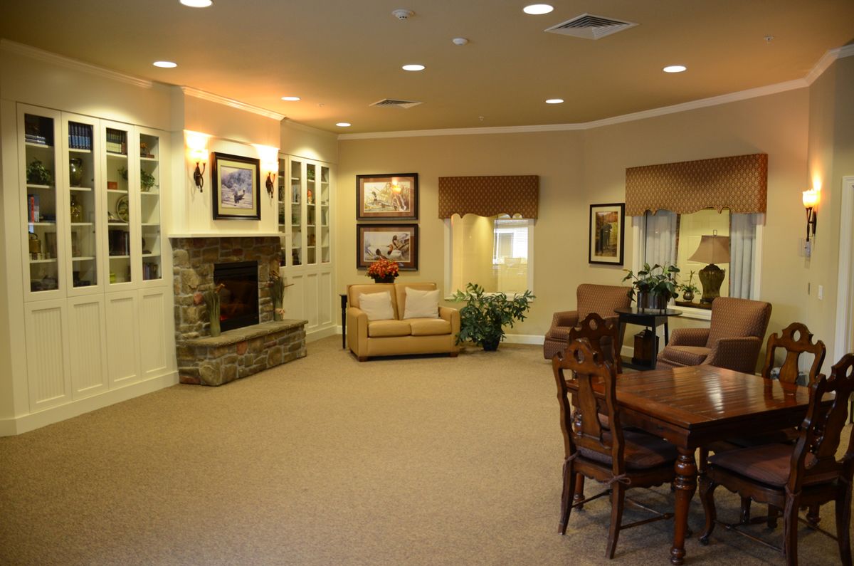 A spacious and elegantly decorated living room featuring a cozy fireplace, comfortable seating, and tasteful artwork.