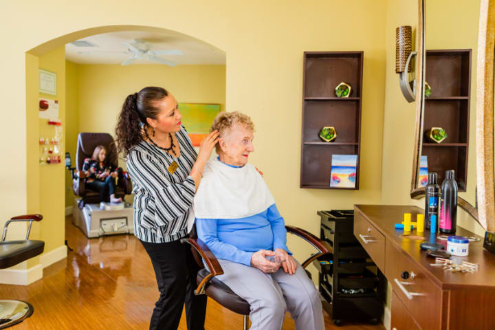 A hairstylist attends to an elderly woman in a salon setting.