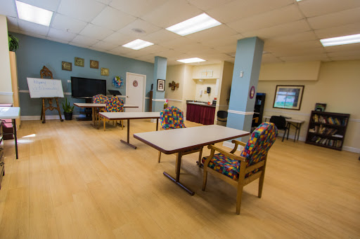 A spacious community lounge area featuring tables and colorful chairs.