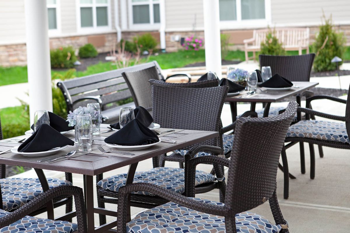 An outdoor patio dining area with tables and chairs elegantly set for a meal.