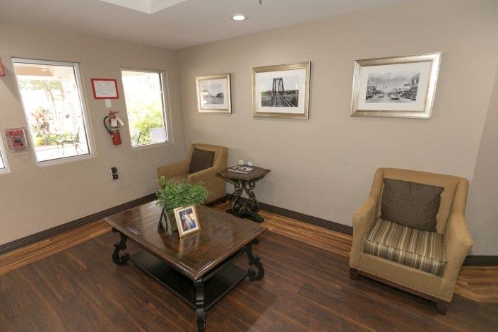 A cozy living room with a coffee table, chairs, and framed artwork on the walls.