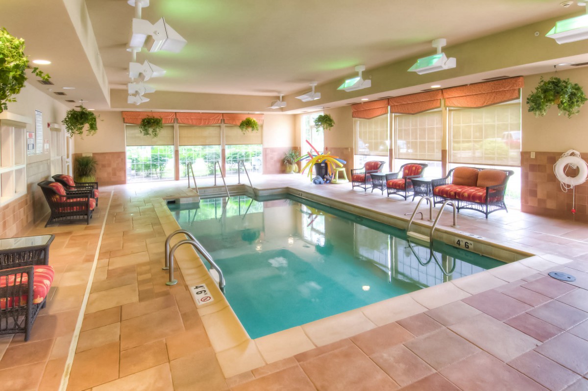 An inviting indoor swimming pool area with comfortable seating and natural lighting.