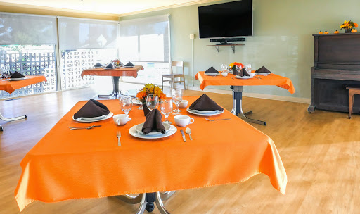 An elegantly set dining area with vibrant orange tablecloths and decorative elements, perfect for a special occasion.