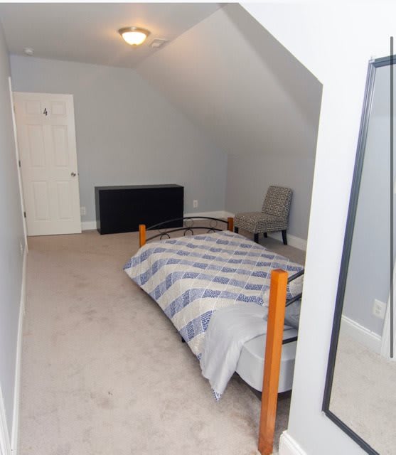 A minimalist attic bedroom with a single bed and chair.