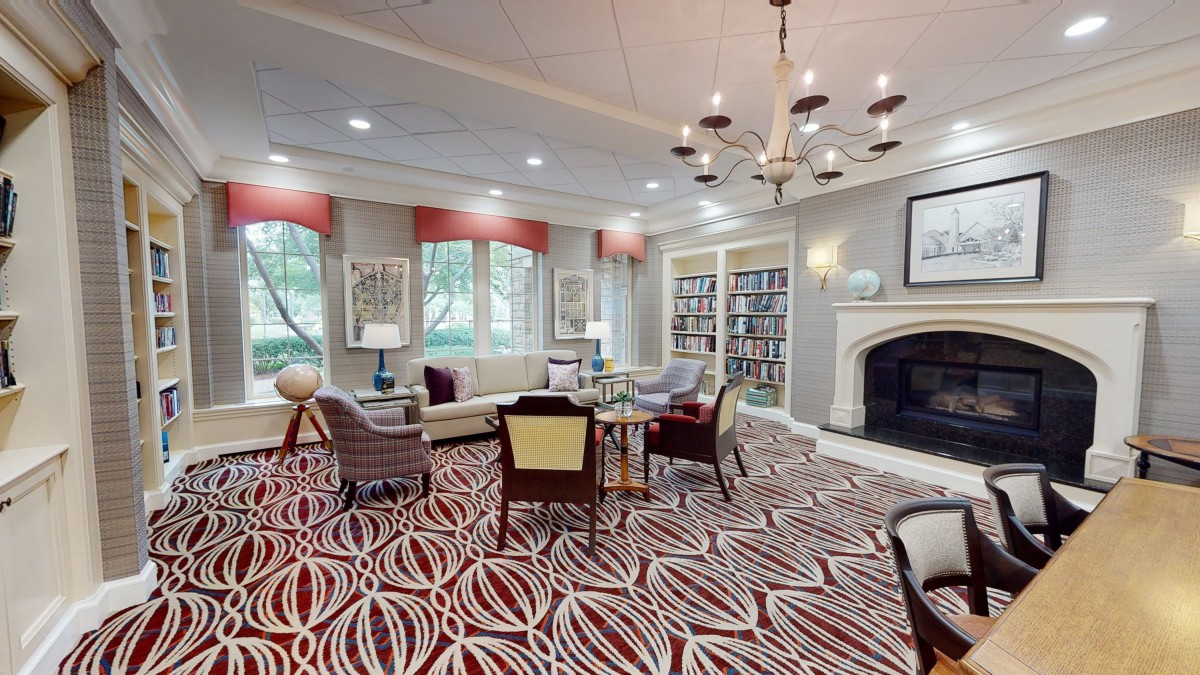 A cozy library interior with comfortable seating, bookshelves, and a fireplace.