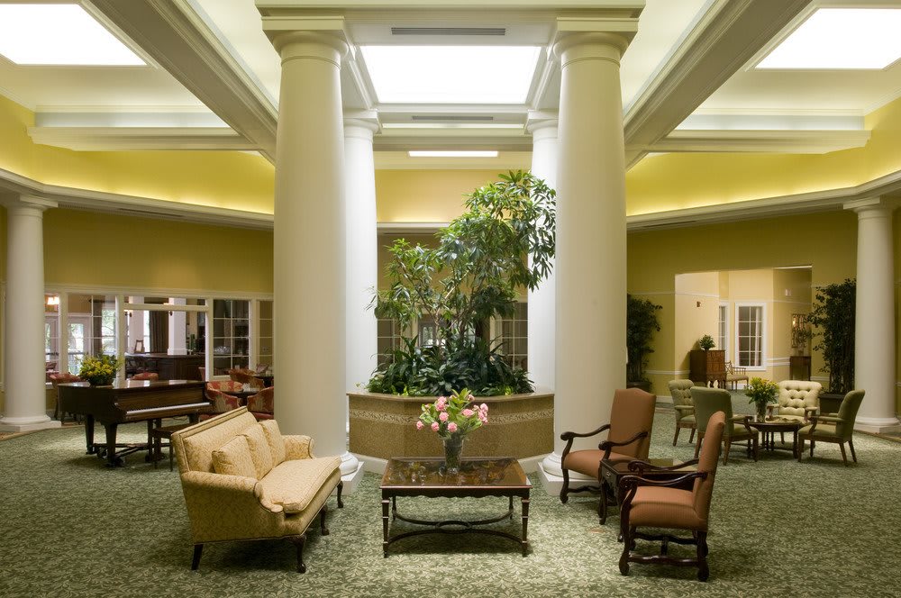 A well-lit lobby featuring elegant furniture, large pillars, and greenery.
