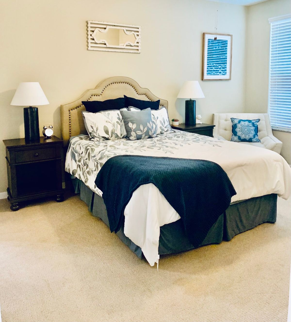 A cozy and well-decorated bedroom with a neatly made bed, nightstands, and lamps.