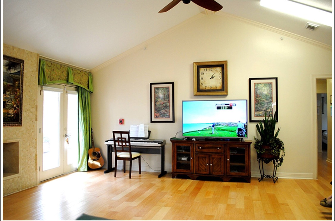 A cozy living room with a piano, television, and decorative artwork.