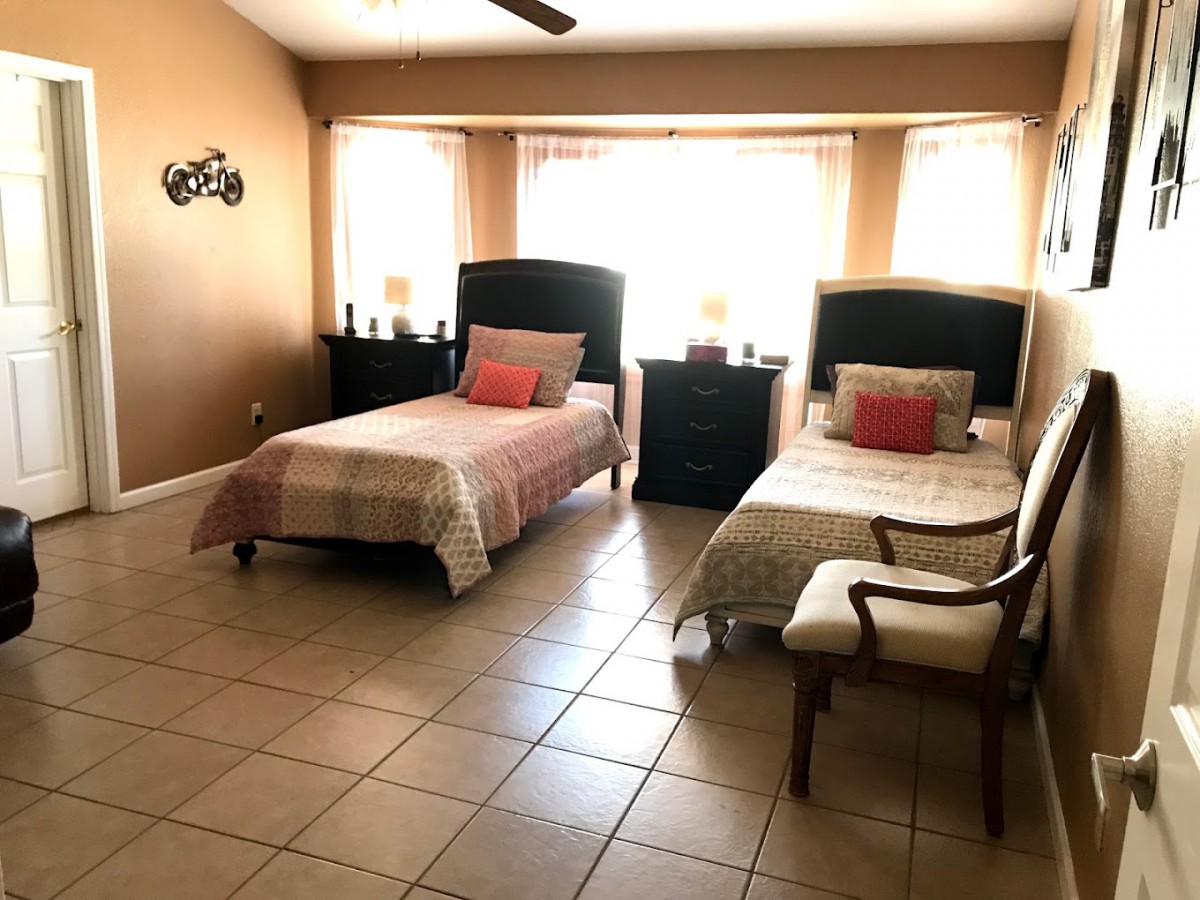 A cozy bedroom with two twin beds and a chair by the window.