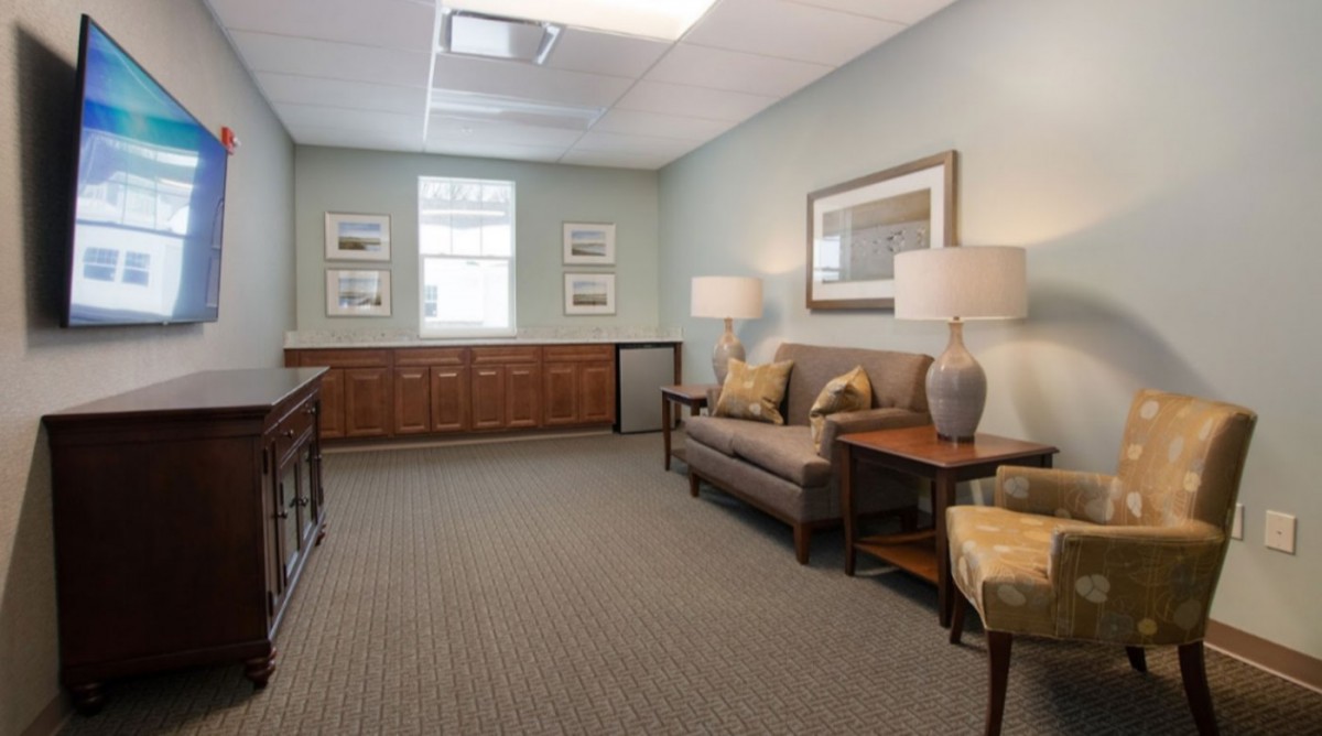 A cozy waiting room with a sofa, lamps, and decor.