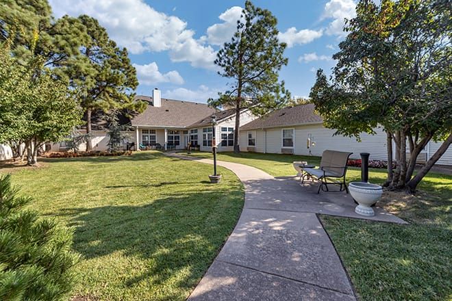 A scenic backyard view of a residential house with a spacious lawn and patio area.
