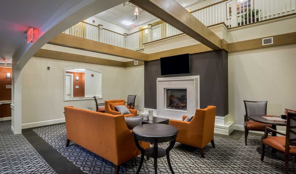 A modern living space with orange sofas and a fireplace in a hotel lobby.