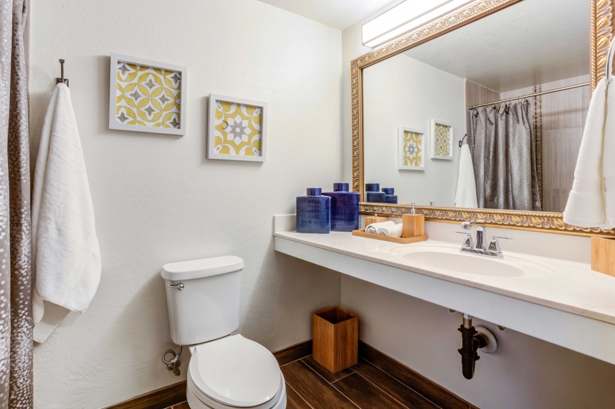 A modern bathroom with a clean design featuring a toilet, sink, and large mirror.