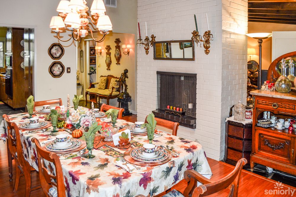 A warmly decorated dining room with a festive table setting and cozy fireplace.