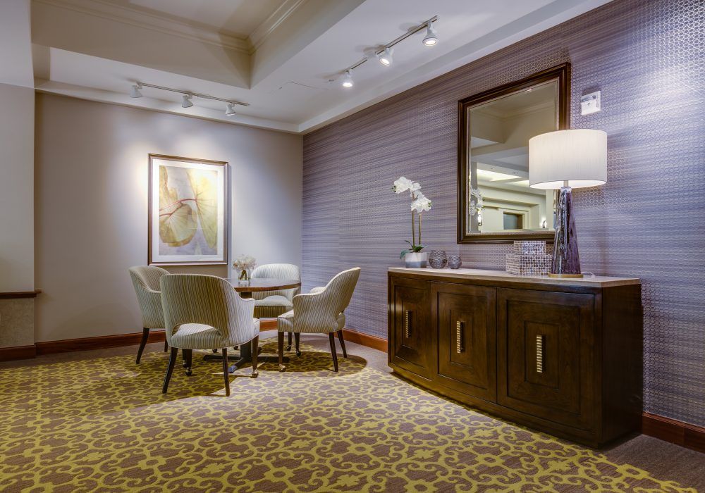 A stylish and modern dining area with elegant furnishings, featuring a table, chairs, a large mirror, and artistic decor.