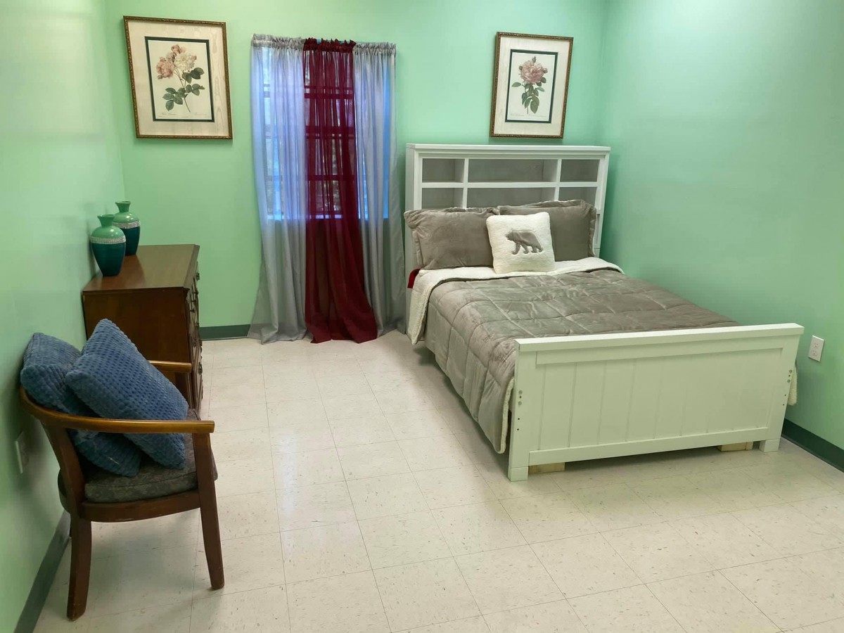 A cozy bedroom with green walls and neatly arranged furniture.