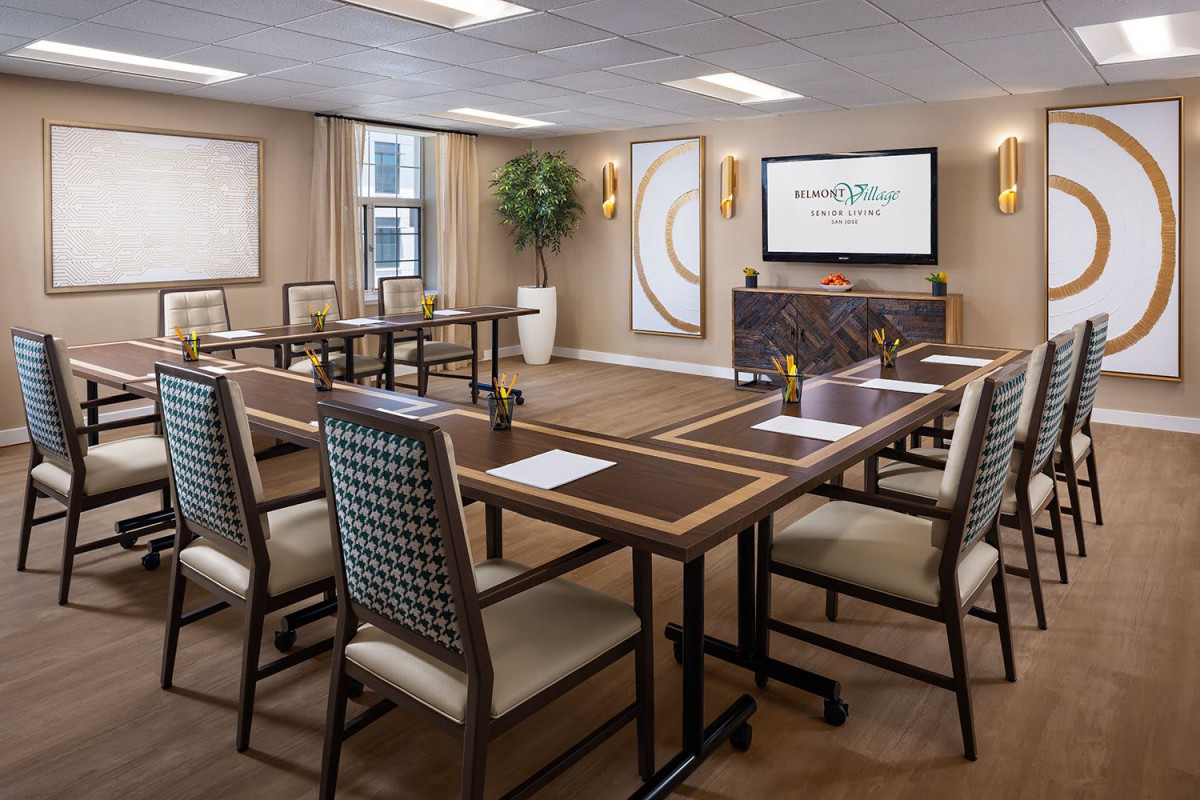 A modern conference room with a U-shaped table setup, notepads, and bottled water prepared for a meeting.
