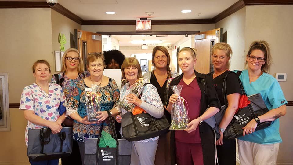 A group of women holding gifts and smiling indoors.