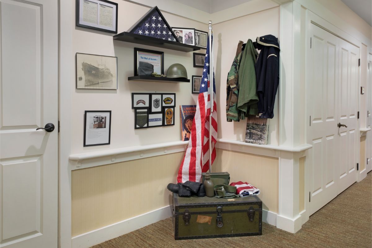 A military memorial display featuring an American flag, uniform, photographs, and memorabilia in a corner setting.
