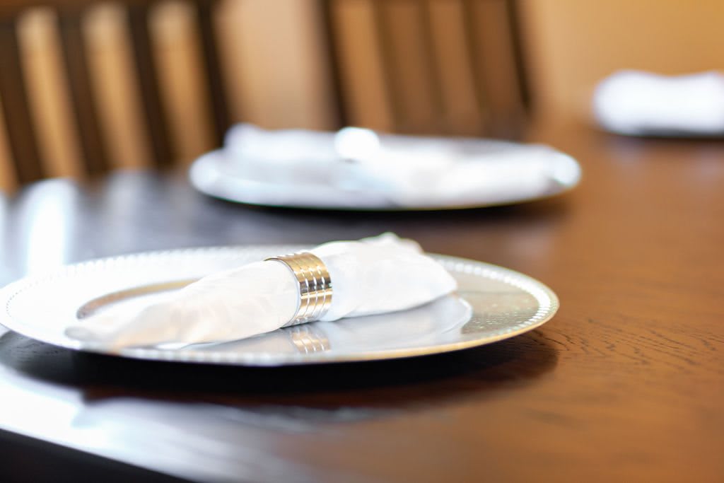 A neatly set dining table with a white napkin and plate.