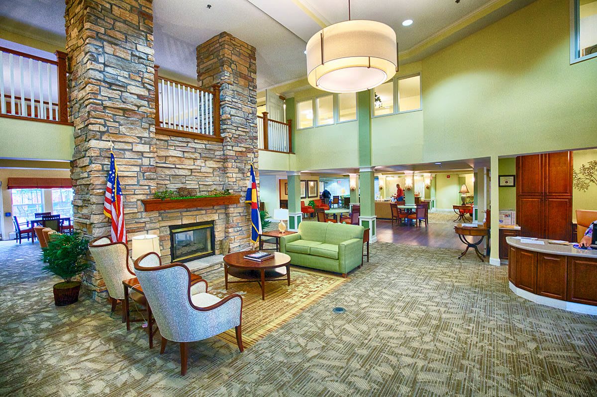 A modern lobby with comfortable seating, a fireplace, and flags on display.