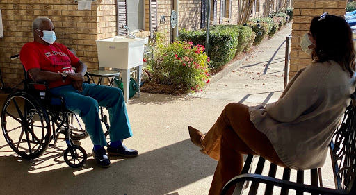 Two individuals sitting outdoors, enjoying a conversation in the sunlight.