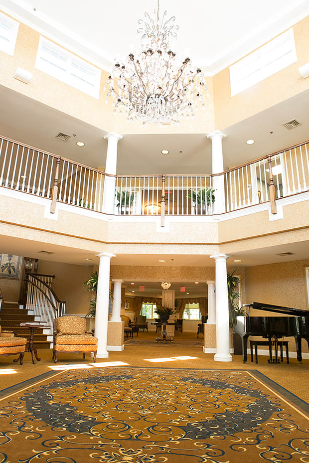 Elegant lobby with a chandelier, featuring a grand piano and comfortable seating.