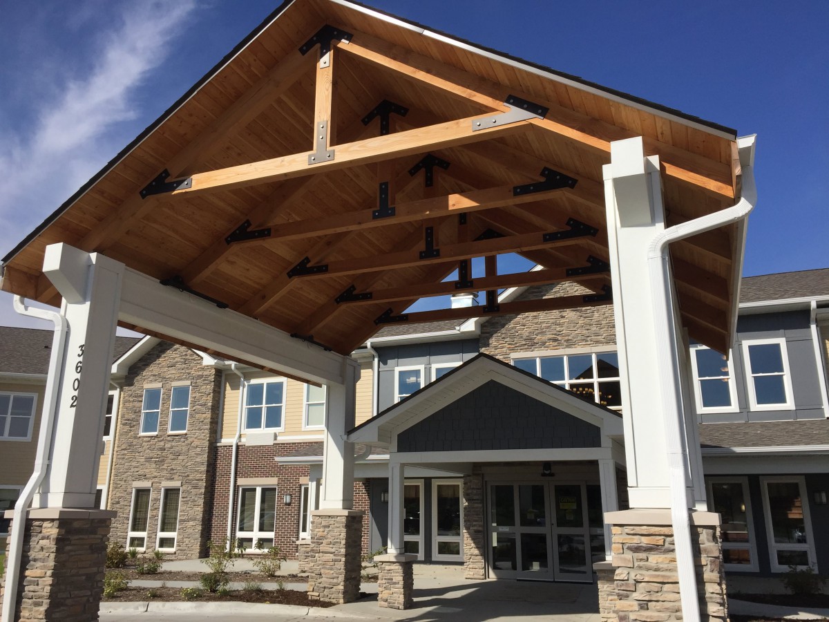A modern building entrance with wooden beams and stone columns.