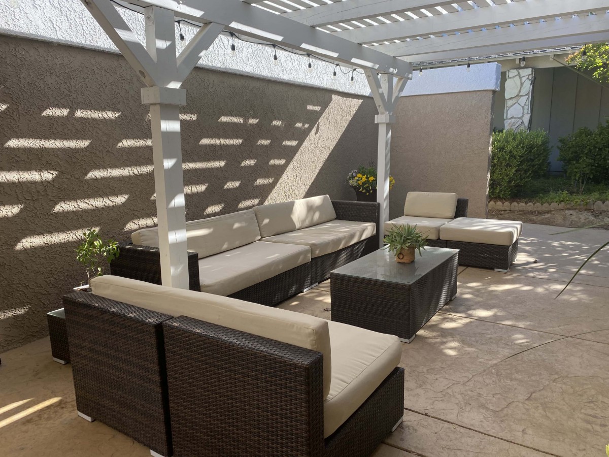 A stylish outdoor patio with comfortable seating under a pergola.